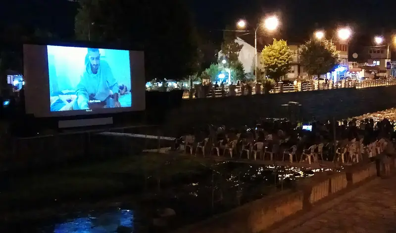 An open-air DokuFest screen over the river in Prizren at night, 2017